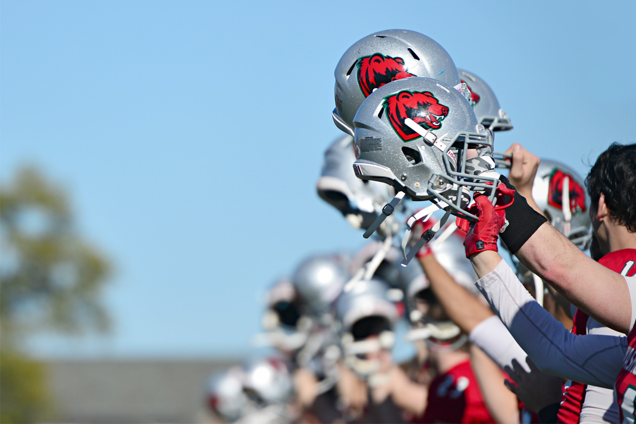 football players raising helmets in-line