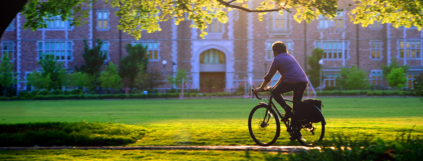 student riding bike on campus featured